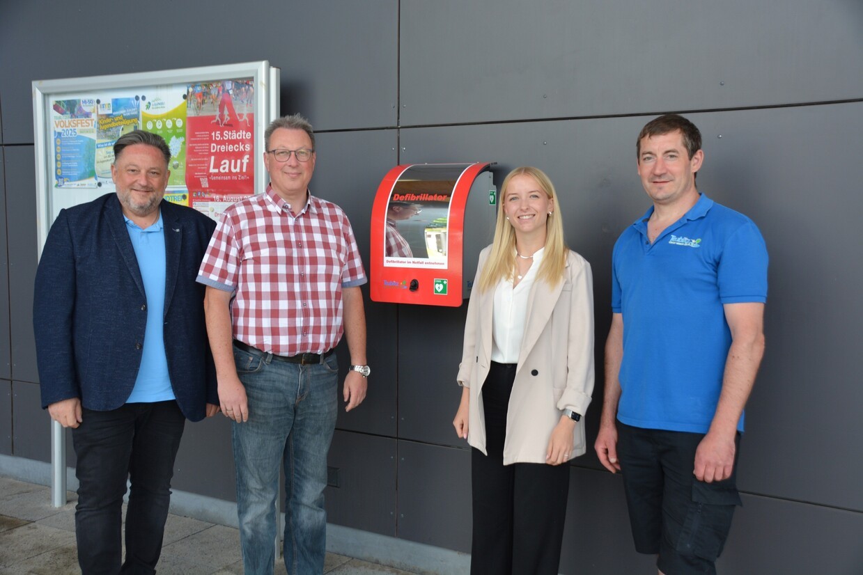 © Bürgermeister Thomas Beer, Kämmerer Georg Beer, Sachbearbeiterin Anna Beer und Hausmeister Florian Winkelmeier (v.li.) vor dem neu-montierten Defibrillator an der Dreisporthalle in Teublitz. Foto: Thomas Stegerer